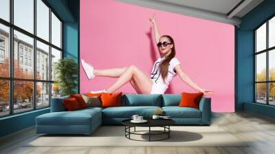 Cheerful young girl with a skateboard on the pink background. Wall mural