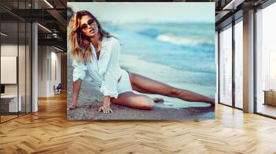 portrait of beautiful sexy caucasian sunbathed woman in sunglasses with long hair in swimsuit lying on summer beach. Wall mural