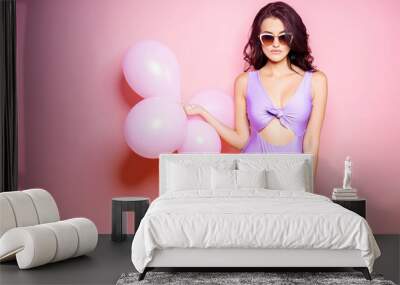 Sexy Lady in bodysuit, sunglasses slim figure, young and healthy posing with balloons on pink background. Skin care and depilation concept. Girl with long hair and smooth skin. Wall mural