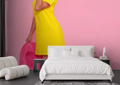 Young smiling woman in yellow dress and hat is looking to camera at the pink copy space. Full length studio shot. Full length portrait of a beautiful smiling woman in dress. isolated. Wall mural