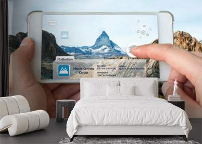 Augmented reality marketing and travel 4.0 concept. Hand holding smart phone use AR application to check relevant information about the spaces around customer. Matterhorn mountain background Wall mural