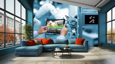 Industry 4.0 concept .Man hand holding tablet with Augmented reality screen software and blue tone of automate wireless Robot arm in smart factory background Wall mural