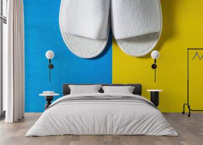 Top view of white slippers on a blue and yellow background. Copy space for text Wall mural