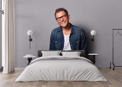 Young man in a denim shirt is smiling Wall mural