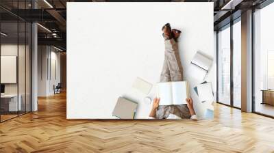 Young man sitting and reading a book on the floor, education concept Wall mural