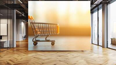 Close-up of an empty shopping cart with yellow accents, placed on a wooden surface, bathed in warm sunlight, creating a serene and minimalist composition. Wall mural