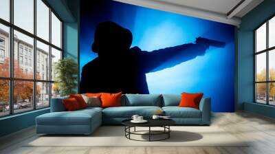 Silhouette of man with assault rifle ready to attack on dark toned foggy background or dangerous bandit in black wearing balaclava and holding gun in hand. Shooting terrorist with weapon theme decor Wall mural