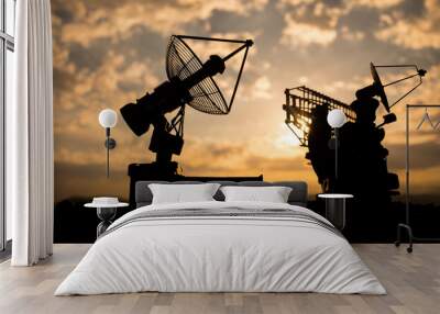 Silhouettes of satellite dishes or radio antennas against sunset sky. Space observatory. Wall mural