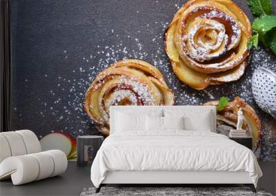 Dish of apple roses baked in puff pastry on a dark concrete background with apples. View from above Wall mural