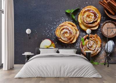 Dish of apple roses baked in puff pastry on a dark concrete background with apples. View from above Wall mural