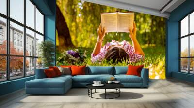 Young woman reading a book in the park with flowers Wall mural