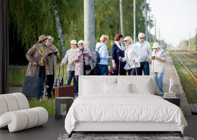 A group of positive senior elderly people travelers using tablets waiting for train before going on a trip.. Wall mural