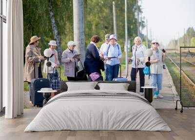 A group of positive senior elderly people travelers using tablets waiting for train before going on a trip Wall mural