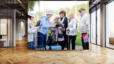 Group of positive senior elderly people looking at digital map on traveling journey during pandemic.COVID-19 travel in the New Normal. Wall mural