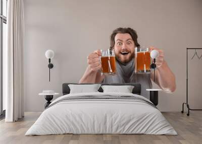 Portrait of a happy young bearded man holding two beer mugs isolated over light gray background Wall mural