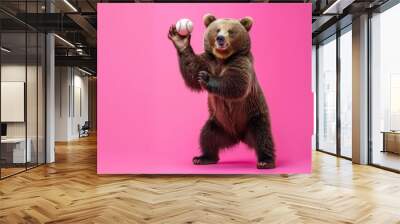 A large brown bear is standing on its hind legs and holding a baseball in its paws. The bear is smiling and looks like it is about to throw the baseball. The background is pink. Wall mural