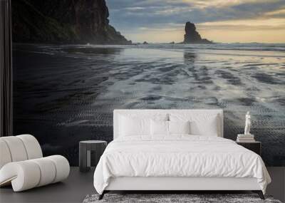 Black sand beach, rocky island and out going tide. Anawhata on the west coast of Auckland, New Zealand. Wall mural