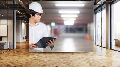 Asian civil engineer or construction worker man wearing protective safety helmet holding document file. Male architect working at construction site. Building and architecture concept Wall mural