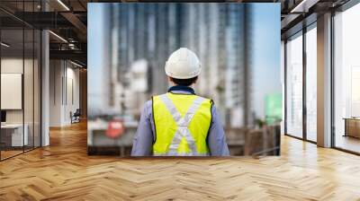 Asian maintenance worker man with safety helmet and green vest standing at construction site. Civil engineering, Architecture builder and building service concepts Wall mural