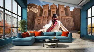 Asian woman tourist in white dress holding her couple hand at Ad Deir or El Deir, the monument carved out of rock in the ancient city of Petra, Jordan. Travel UNESCO World Heritage Site in Middle East Wall mural