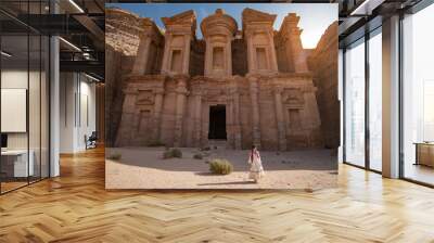 Asian woman tourist in white dress standing at Ad Deir or El Deir, the monument carved out of rock in the ancient city of Petra, Jordan. Travel UNESCO World Heritage Site in Middle East Wall mural