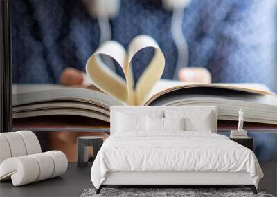 Book lover or love reading concepts. Male hand holding book with heart shape page folded. Wall mural