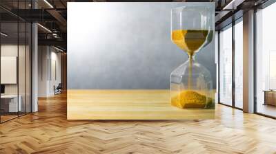 Gold sand running through the shape of modern hourglass on wooden table.Time passing and running out of time. Urgency countdown timer for business deadline concept Wall mural