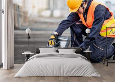 Male Asian mechanic or maintenance worker man wearing protective suit and helmet opening work tool box at construction site. Equipment for mechanical engineering project Wall mural