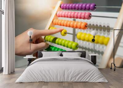 Male hand calculating with beads on wooden rainbow abacus for number calculation. Mathematics learning concept Wall mural