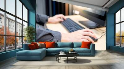 Male hand holding computer mouse while using desktop computer in furniture store. Interior material design simulation program for customer. Home improvement concept Wall mural