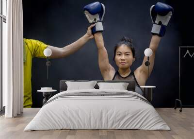 Referee lifting young female boxer hand, winner of the match. Boxing training concept Wall mural