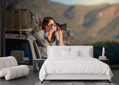 Young Asian woman traveler and photographer sitting on the car window taking photo on road trip in Namibia, Africa. Travel photography concept Wall mural