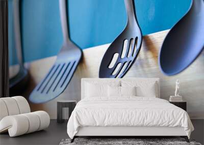 Cooking utensils hanging on the kitchen wall, blue minimal spoon household background Wall mural