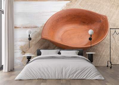 Empty clay brown bowl on white wooden background and linen textile. Side view. Wall mural