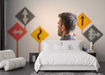 A man in a plaid shirt stands facing multiple road signs, symbolizing choice and direction. The signs include arrows pointing in different directions, conveying a sense of decision-making or confusion Wall mural