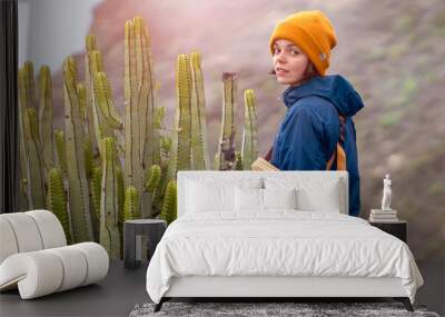 A young girl is trekking, hiking in the mountans among exotic plants and cacti. Wall mural