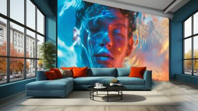 An underwater close-up portrait of a person with closed eyes, bathed in a blend of blue and orange light. The shimmering water and vibrant colors create a surreal and tranquil atmosphere. Wall mural