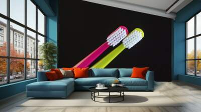 Two bright toothbrushes close-up on a black background. Wall mural