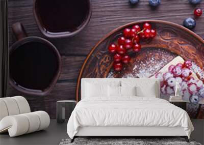 Two pieces of puff cake with fresh berries and sugar powder on brown plate and two brown cups of coffee on dark wooden table. Wall mural