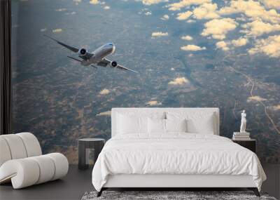 Airplane flying at high altitude over green mountains and sky at sunrise Wall mural