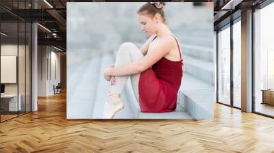 Ballerina girl sits on the steps in a ballet dress Wall mural