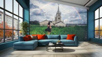 The rainbow in the church and the back of the girl on the grass Wall mural