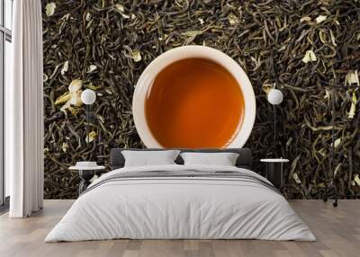 a cup of jasmine scented tea on dried tea leaves background Wall mural