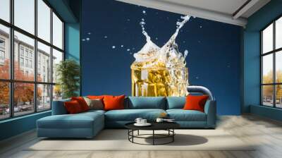 glass of splashing beer on blue background Wall mural