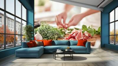 Close-up of hands skillfully preparing fresh ingredients for a traditional Italian meal, featuring prosciutto, leafy greens, and vibrant vegetables on a rustic table. The scene captures the essence of Wall mural