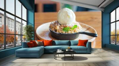 Apple crumble topping vanilla ice cream serve with iron pan and wooden tray on table. Wall mural