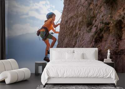 rock climber boy. child is practicing rock climbing. summer camp. sport in nature. cute teenager climbing on a rock with belay Wall mural