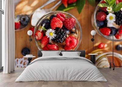 Dessert of various berries with fresh mint and edible daisy flowers, top view. Healthy and delicious breakfast. Wall mural