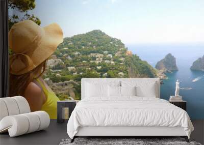 Beautiful young female model with straw hat in Capri Island with Faraglioni sea stack and blue crystalline water on the background, Capri, Italy. Banner panorama. Wall mural