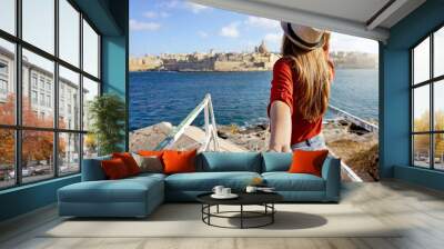 Follow me in Malta. Young carefree tourist woman in hat holds boyfriend hand and looking panoramic view of Valletta, Malta. Couple on summer holiday vacation. Traveling together. Wall mural